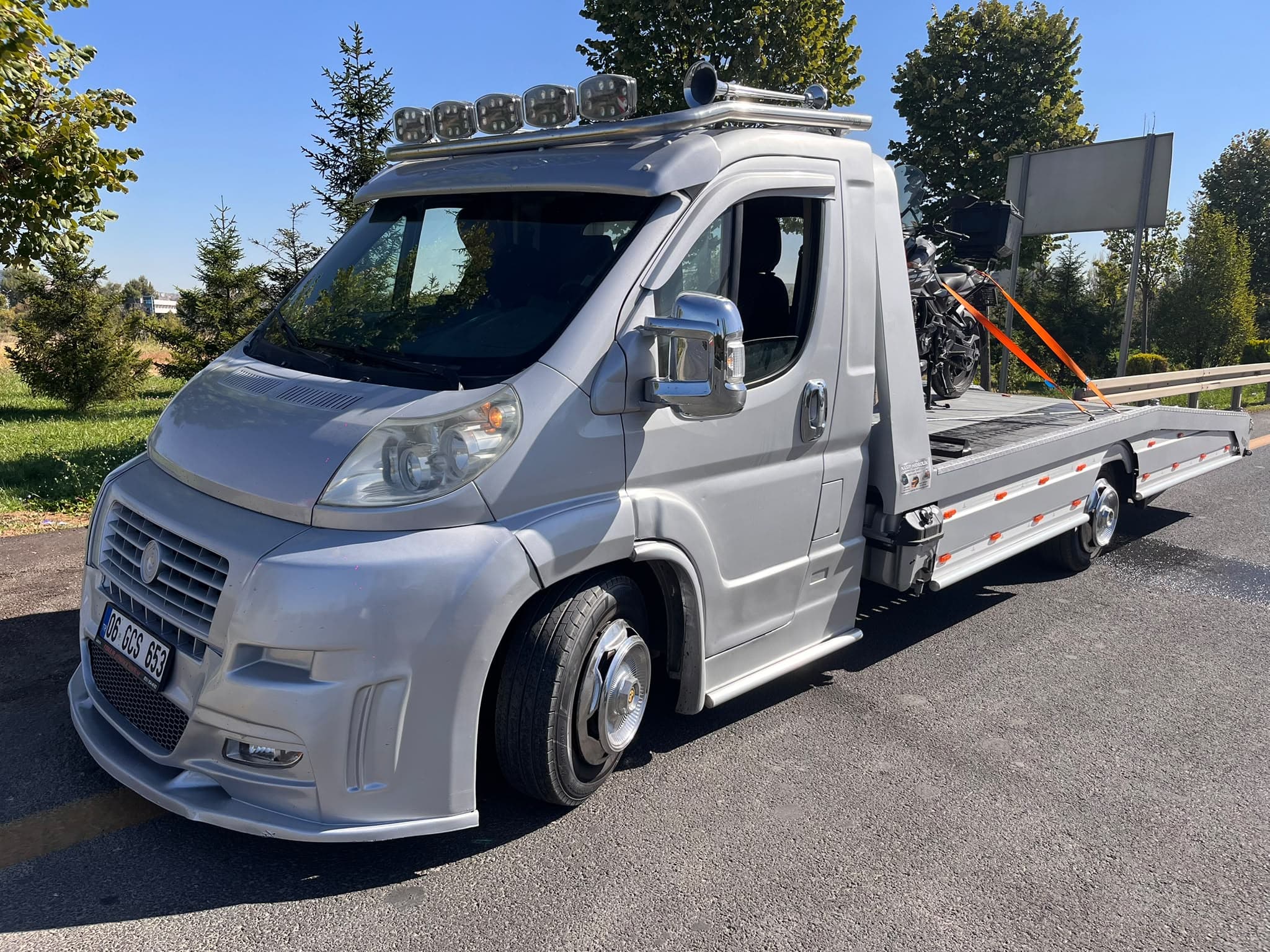 Prime Oto Kurtarma çekicisi bir motosikleti platformuna sabitleyip şehir dışı yolda ilerliyor